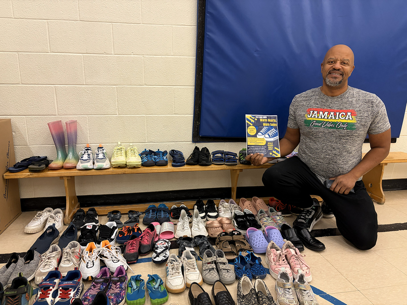 Photo of shoes collected with staff member holding a flyer advertising the collection