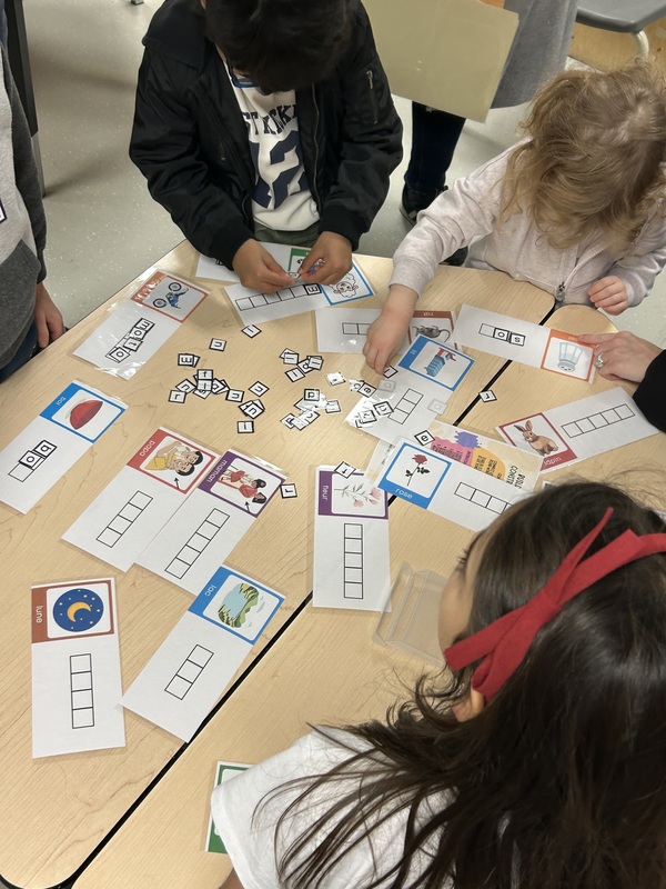 Adults and children participating in an activity in a classroom.