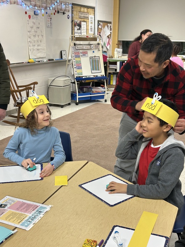 Adults and children participating in an activity in a classroom.