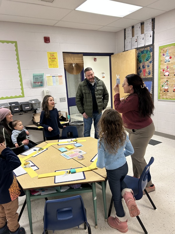 Adults and children participating in an activity in a classroom.