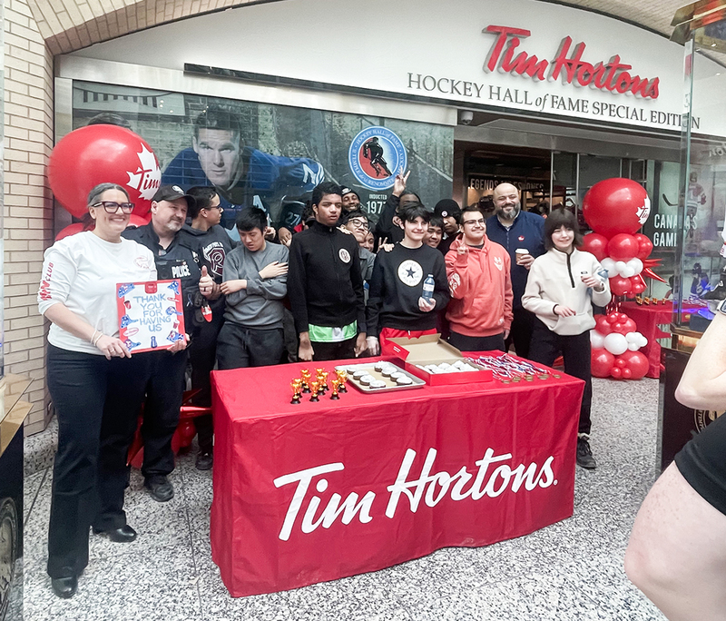 Photo of St. Oscar Romero ISP students, staff, Tim Hortons owner, police officer and more with the donuts, trophies and medals