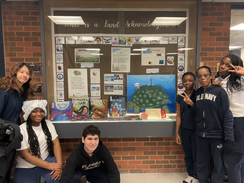Photo of St. Angela students posing with the Land Acknowledgement display that they created