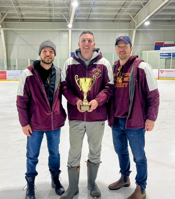 Three faculty posing on the ice while holding an award
