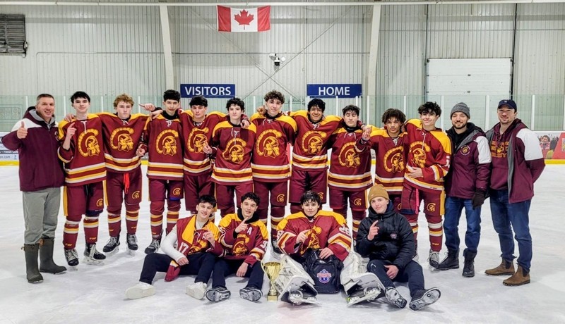 A hockey team posing in uniforms on the ice. 