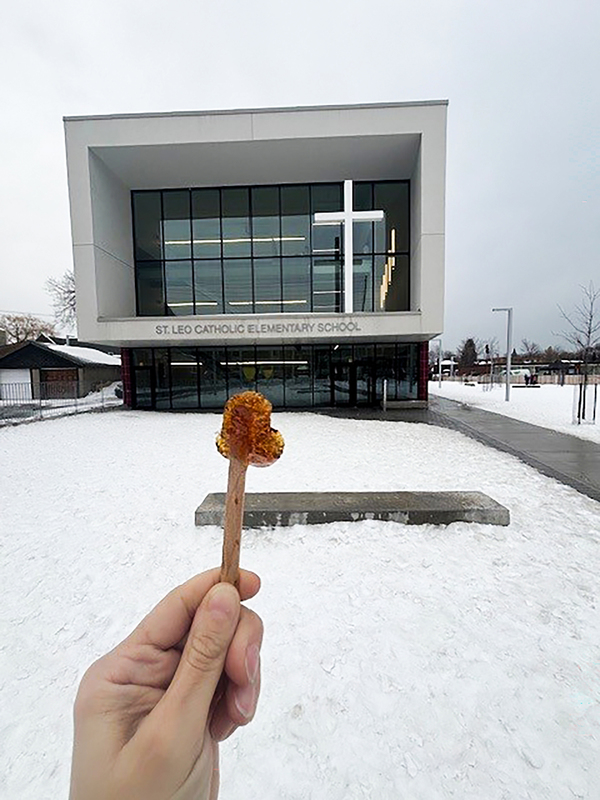 Holding up a taffy in front of the St. Leo school building