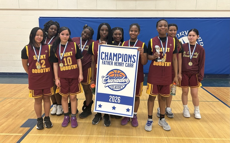 A girls basketball team photo in the gym, holding up a Champions 2026 banner