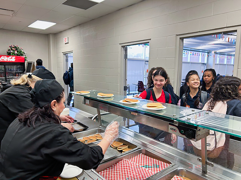 Photo of Redmond students being served pancakes by the staff