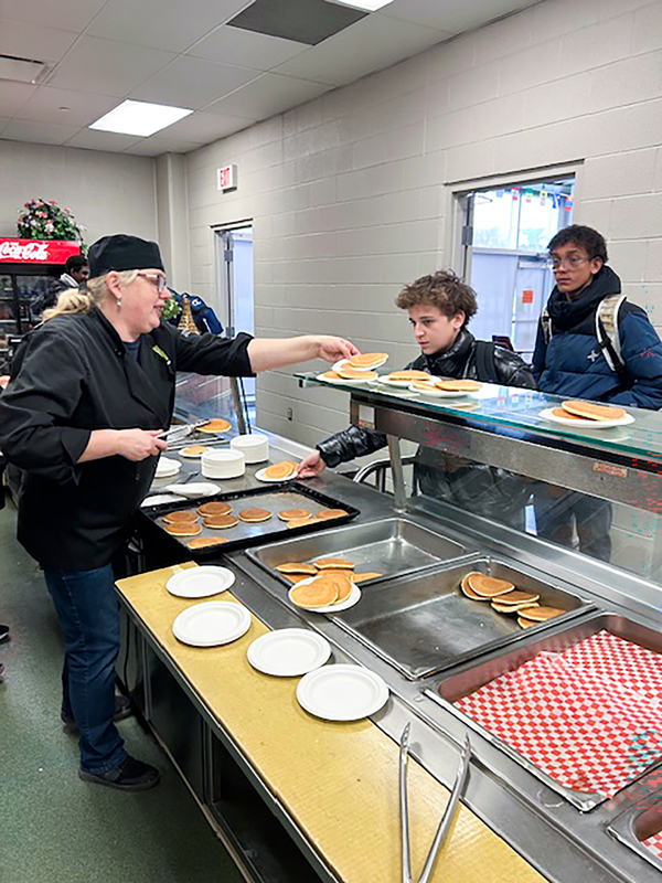 Photo of Redmond students being served pancakes by the staff