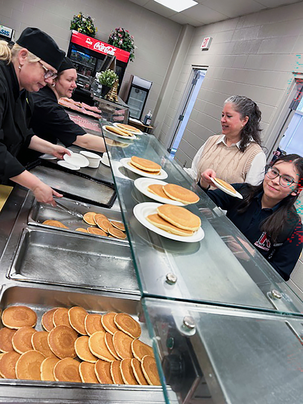 Photo of Redmond students being served pancakes by the staff
