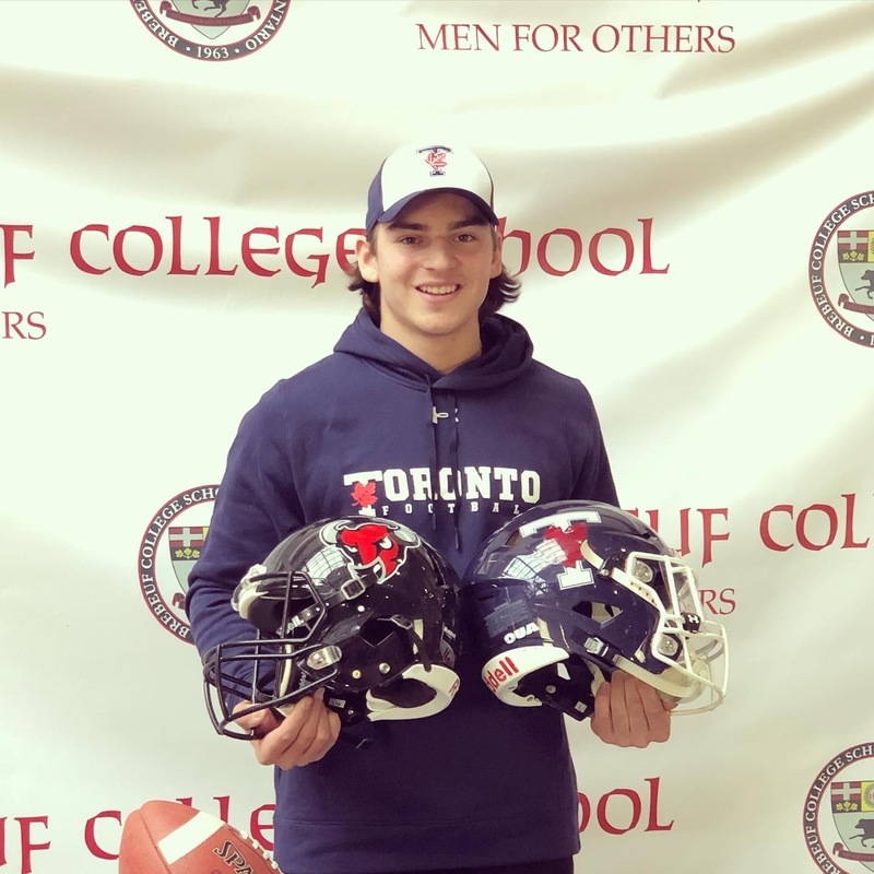 Photo of Luka holding two football helmets during his Brebeuf years