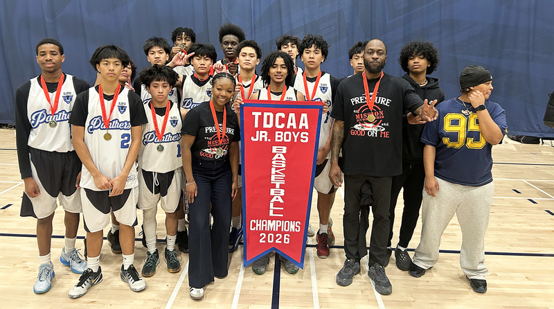 Group photo of SJPII basketball team with their championship banner