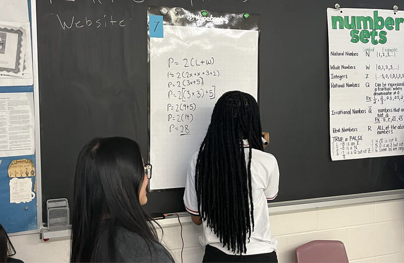 Photo of students working on math sums together on the board