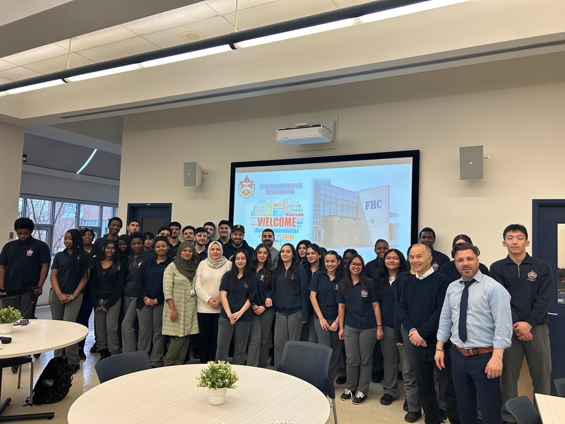 Large group of students and adults in front of a projector that reads "Welcome"