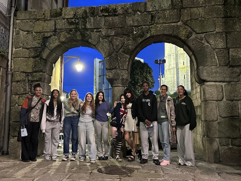 Group of teens with an adult posing outdoors in front of a european background