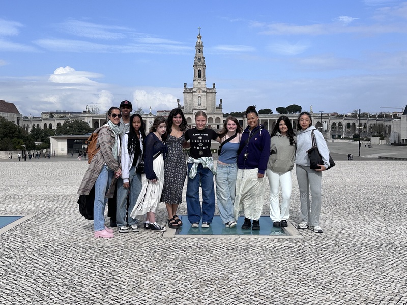 Group of teens with an adult posing outdoors in front of a european background