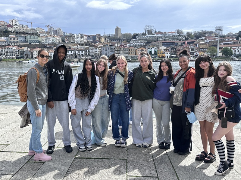 Group of teens with an adult posing outdoors in front of a european background