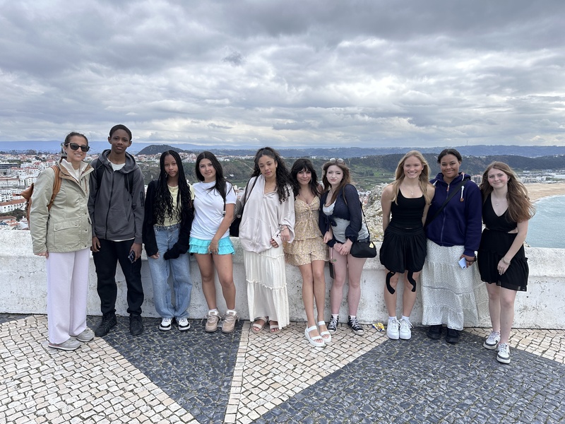 Group of teens with an adult posing outdoors in front of a european background