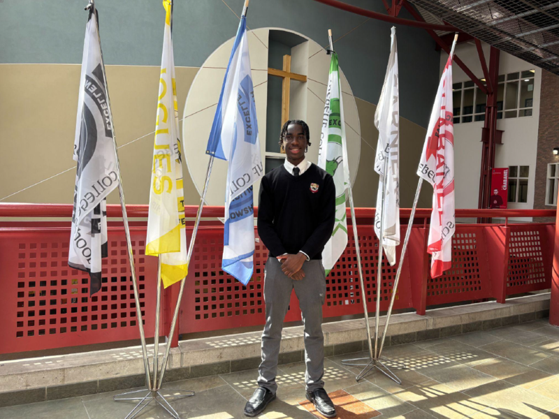 Student posing in uniform in front of flags.