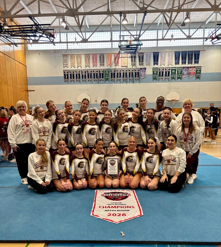 A group of girls sitting in a gym in cheerleading uniforms
