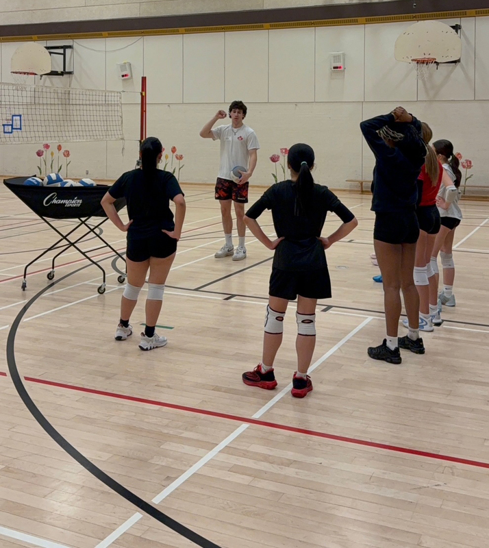 Photo of Mason coaching SJCS athletes on the court