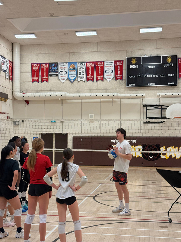 Photo of Mason coaching SJCS athletes on the court