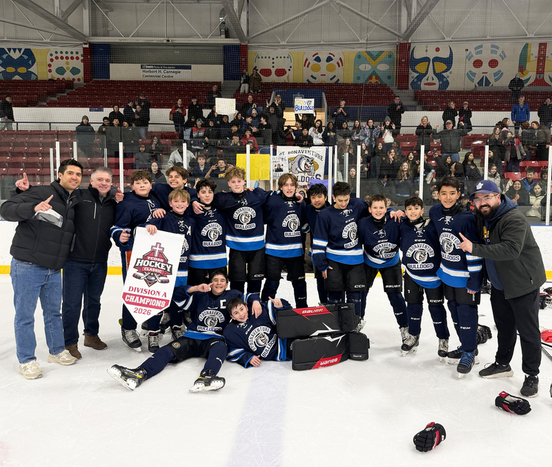 Group photo of the St. Bonaventure ice hockey team on the ice with their championship banner