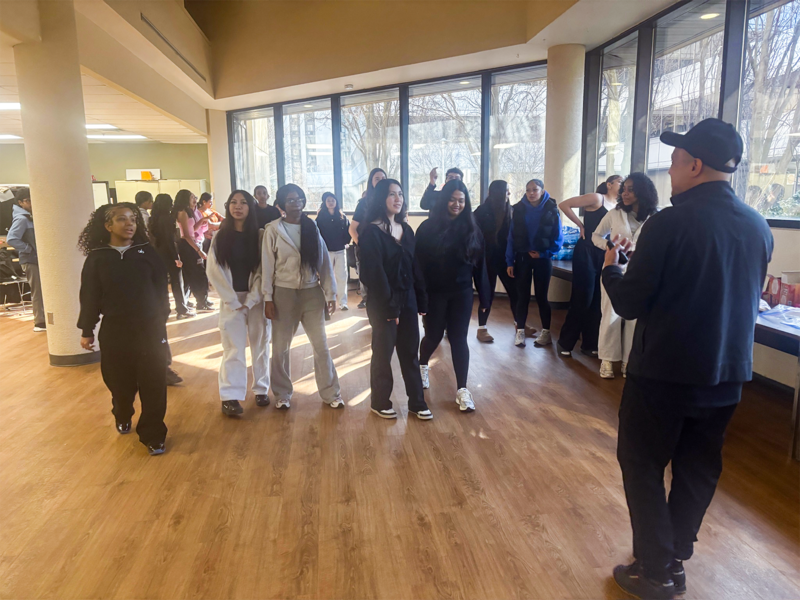 Photo of Glendale Reyes teaching Newman students the foundations of breakdancing