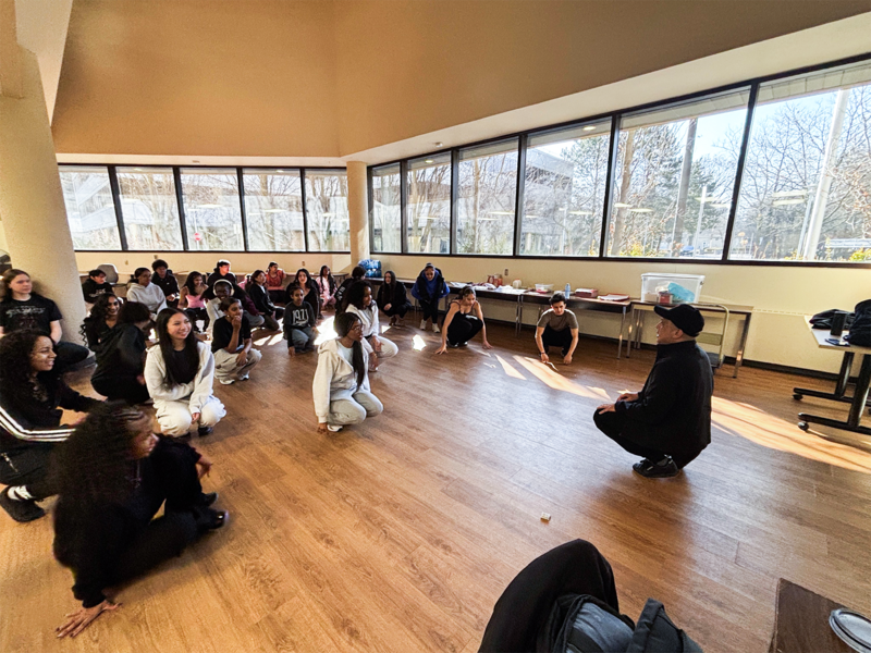 Photo of Glendale Reyes teaching Newman students the foundations of breakdancing