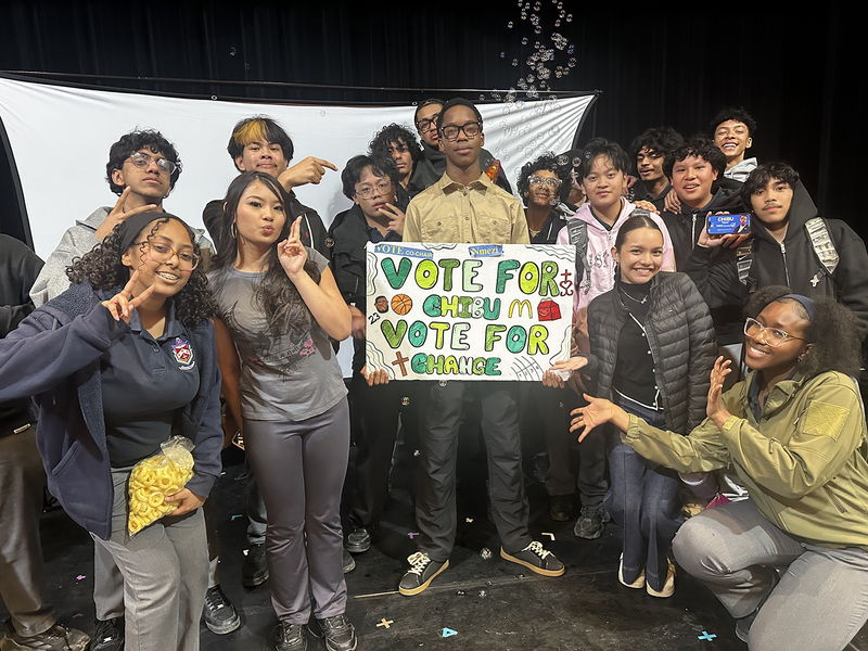 Photo of Chibu with one of his campaign posters and the students supporting him