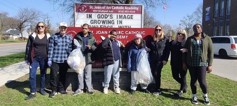 Group photo of SJOA students and staff with the garbage they cleaned up, posting in front of the school name sign