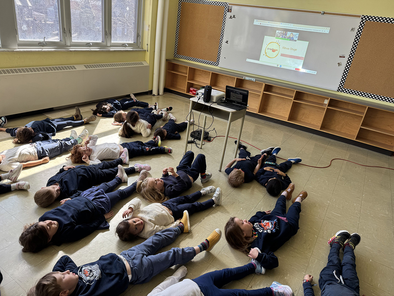 Photo of the students watching the presentation while lying on the classroom floor