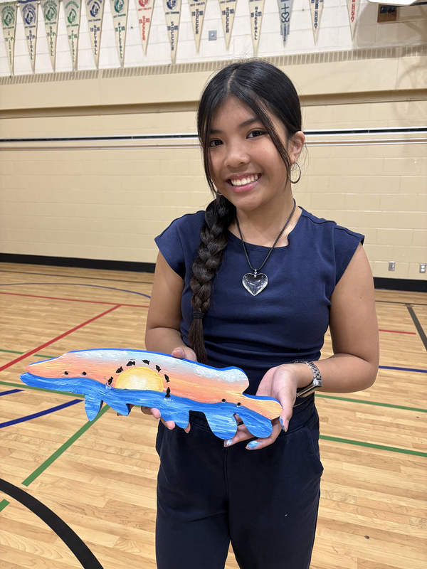 Photo of a student holding up the fish she coloured