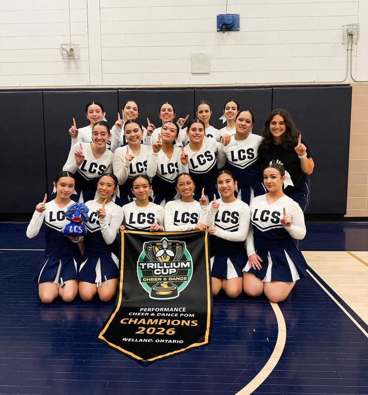 Photo of the Loretto College School Lightning Pom team posing with their championship banner