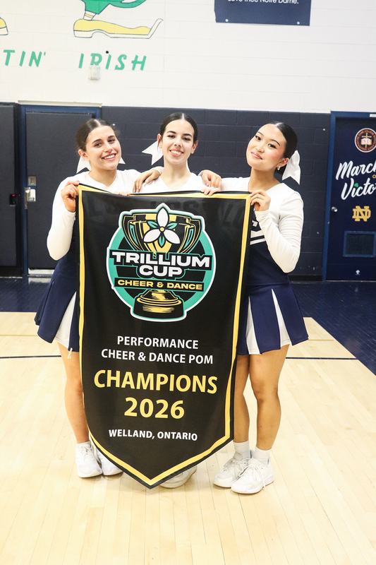 Photo of the Loretto College School Lightning Pom team posing with their championship banner
