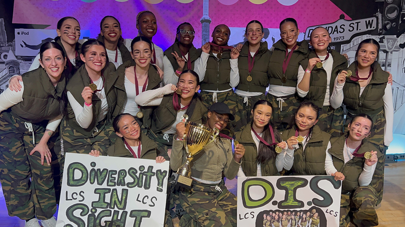 Group photo of the Dance Team with their team banners and championship trophy and medals