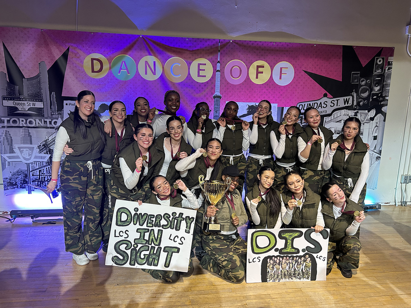 Group photo of the Dance Team with their team banners and championship trophy and medals