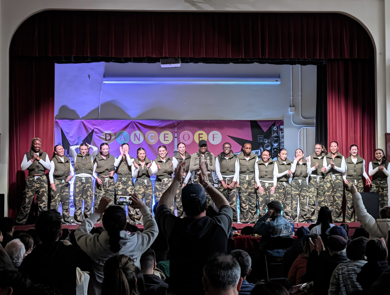 Group photo of the Dance Team on stage being applauded after their performance