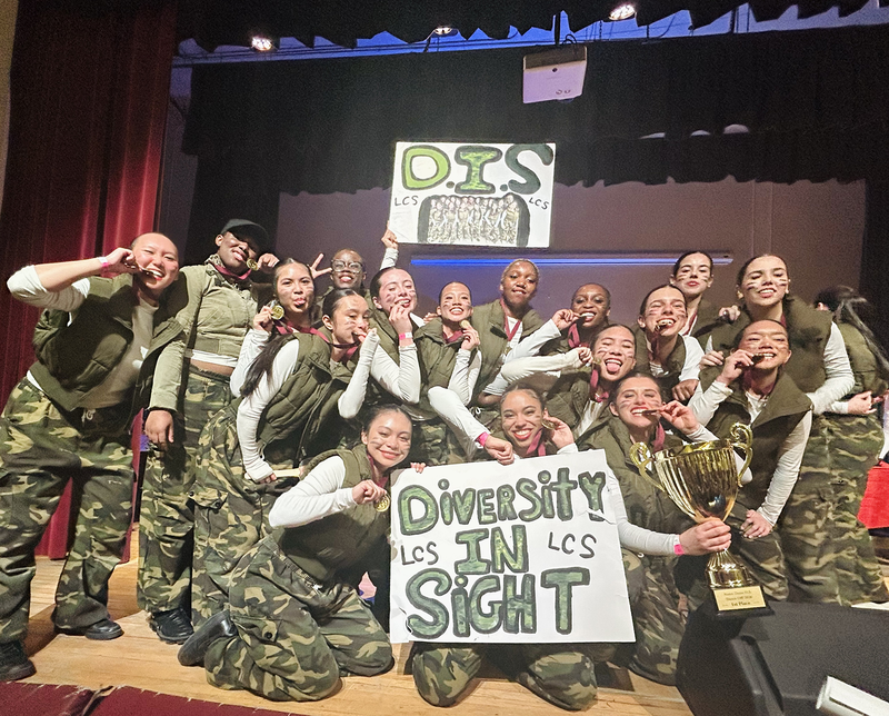 Group photo of the Dance Team with their team banners and championship trophy and medals