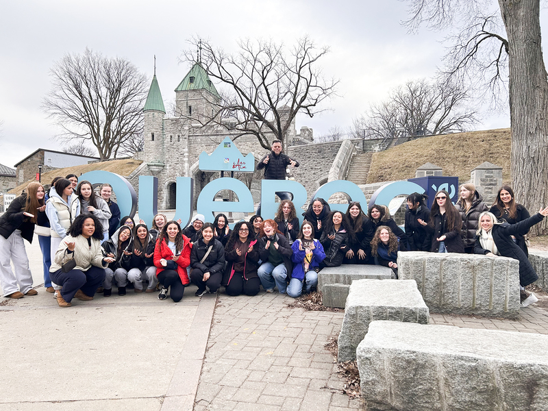 Photo of SJCS students and staff in front of blue Quebec sign