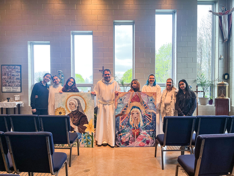 Photo of Loretto College students with Father Gustavo Campo and the two murals