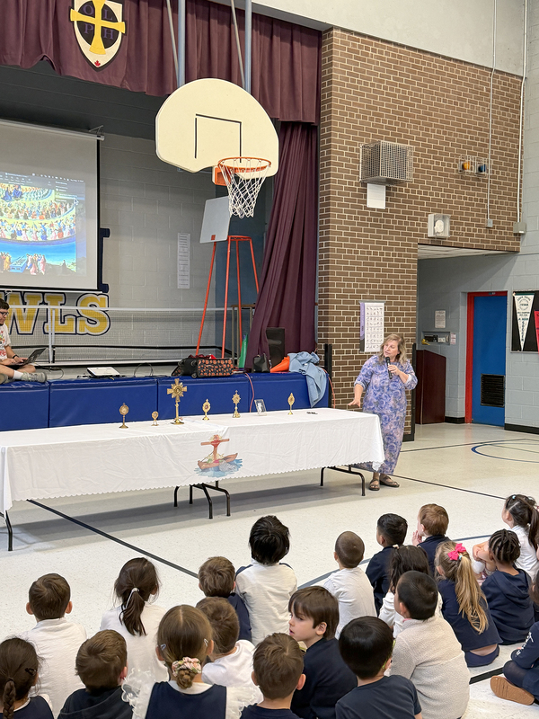 Photo of Mrs. Moon presenting to the lyrics to OLPH students