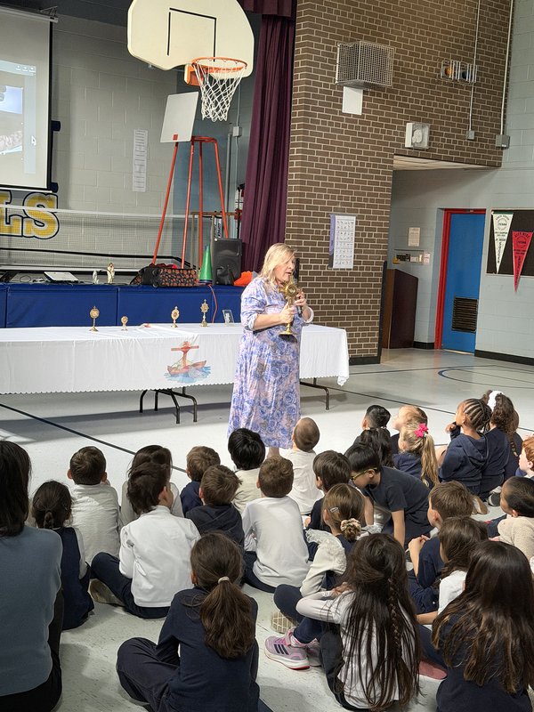 Photo of Mrs. Moon presenting to the lyrics to OLPH students