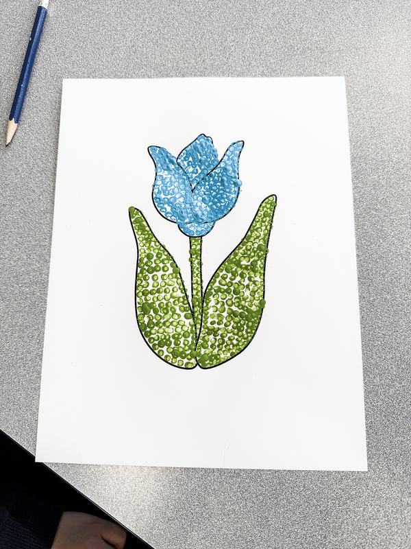 Photo of one of the artworks created during the session of a blue flower with green leaves