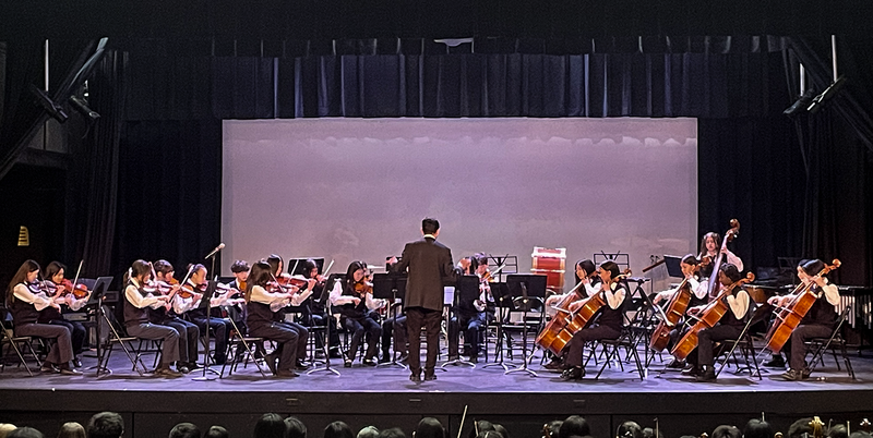 Photo of teacher conducting TCDSB music students on the stage