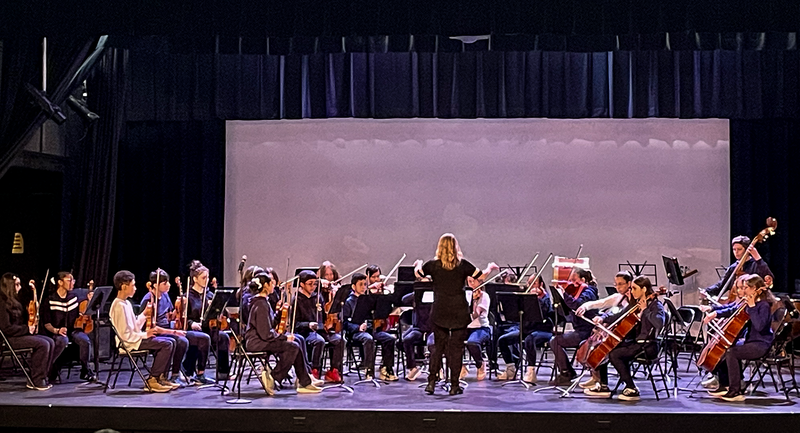 Photo of teacher conducting TCDSB music students on the stage