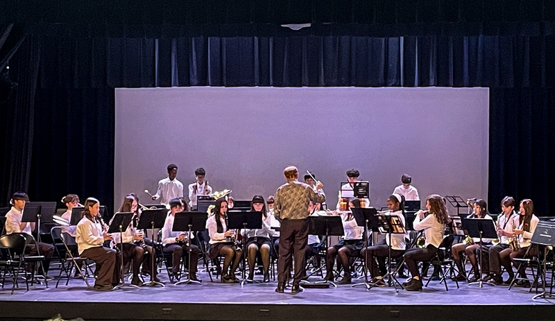 Photo of teacher conducting TCDSB music students on the stage