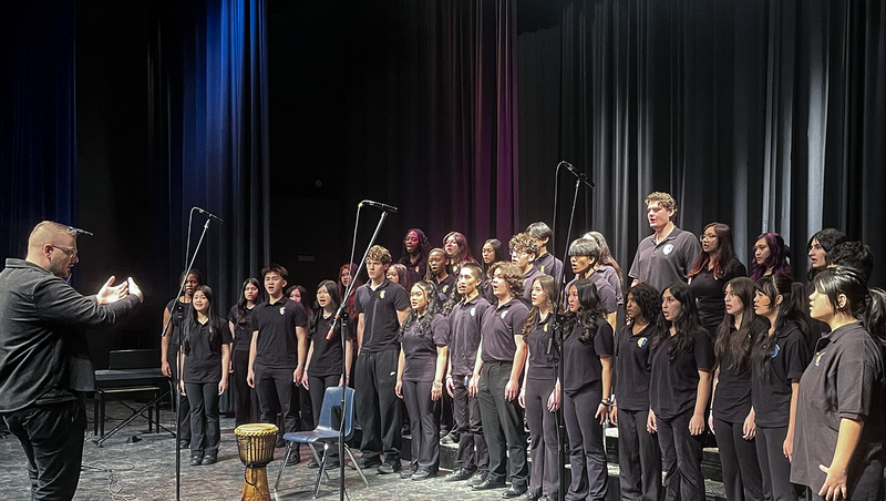 Photo of teacher conducting TCDSB music students on the stage