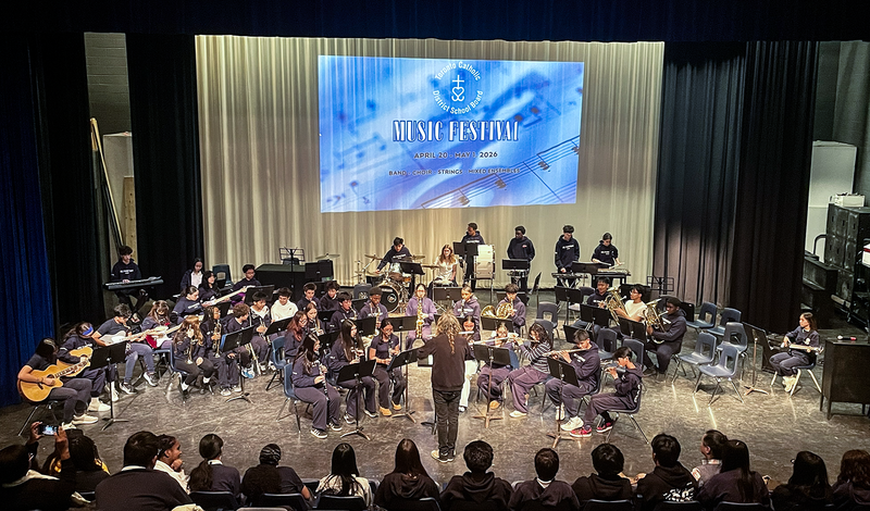 Photo of teacher conducting TCDSB music students on the stage