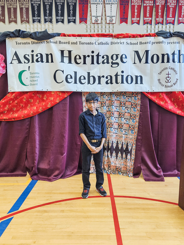 Photo of Evan standing in from of a banner that says Asian Heritage Month Celebration