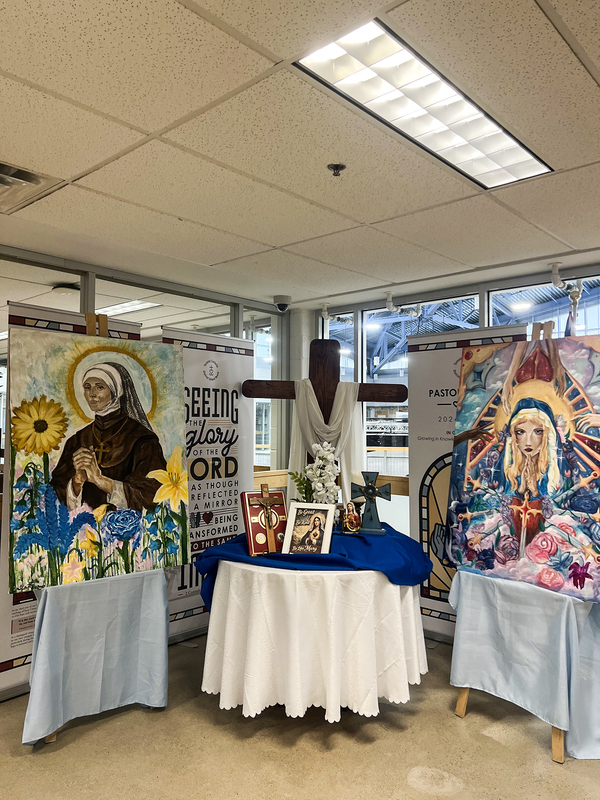 Banner showing Mary display with two paintings and other Mary-related displays and crosses